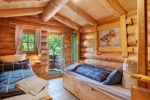 A log cabin bedroom with a bed, a bench, and a window. - Chalet 'Tiny Hideaway' with Mountain Views, Private Terrace, and Private Garden (Sankt Englmar)