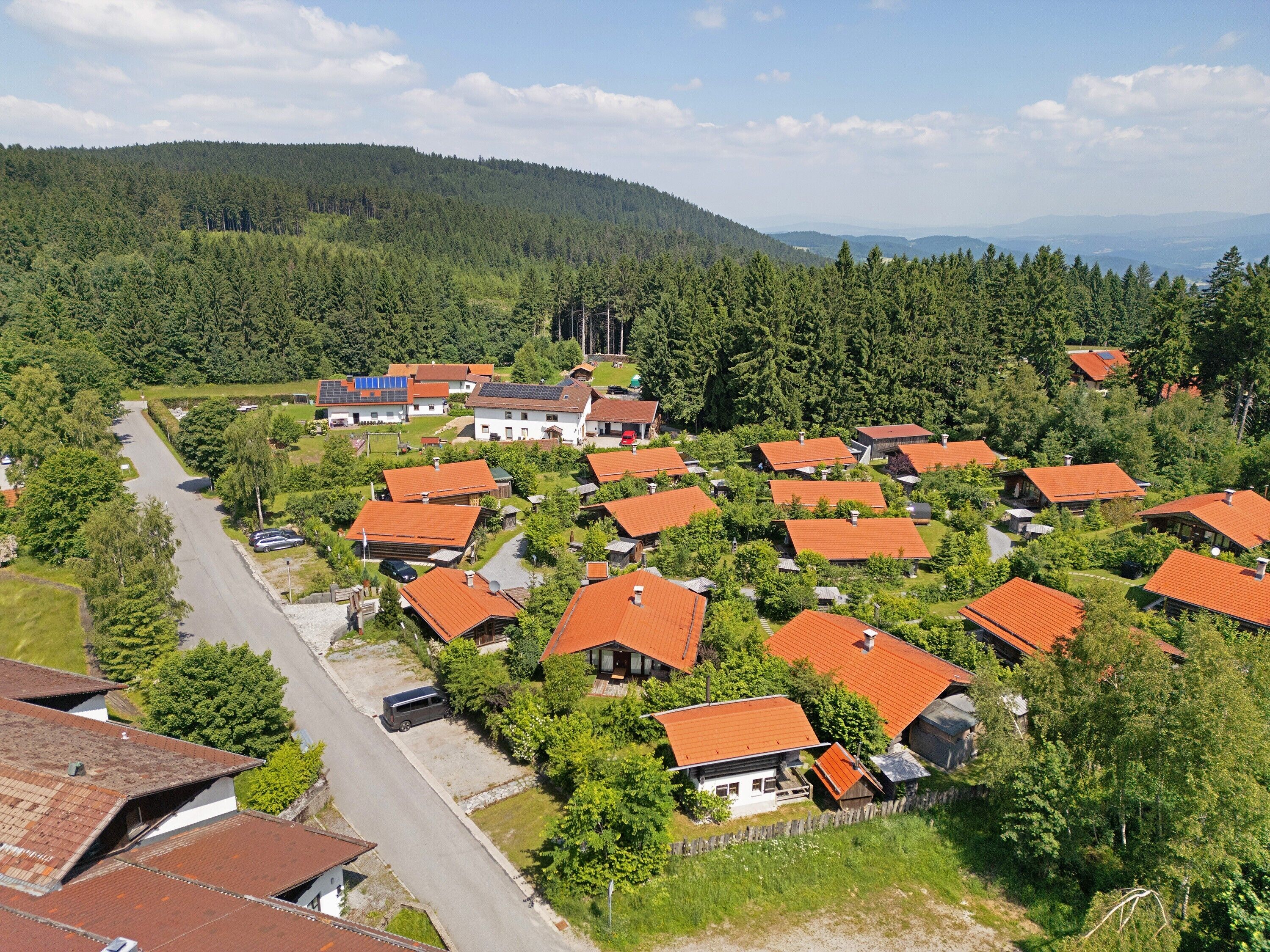 Zona residencial con casas de techos rojos, rodeada de vegetación y un paisaje montañoso.