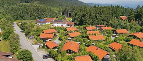 Zona residencial con casas de techos rojos, rodeada de vegetación y un paisaje montañoso.