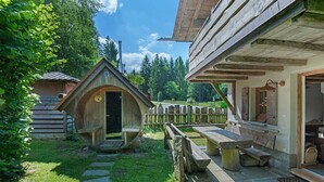 Una cabana rústica de fusta amb una porta de fusta, una banca i un camí de pedra.