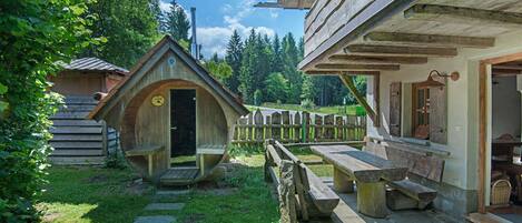 Una cabaña rústica de madera con puerta de madera, un banco y un camino de piedra.