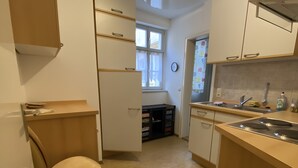 Kompakti keittiö, jossa on sisäänrakennettu liesi, pesuallas ja tuoli.
