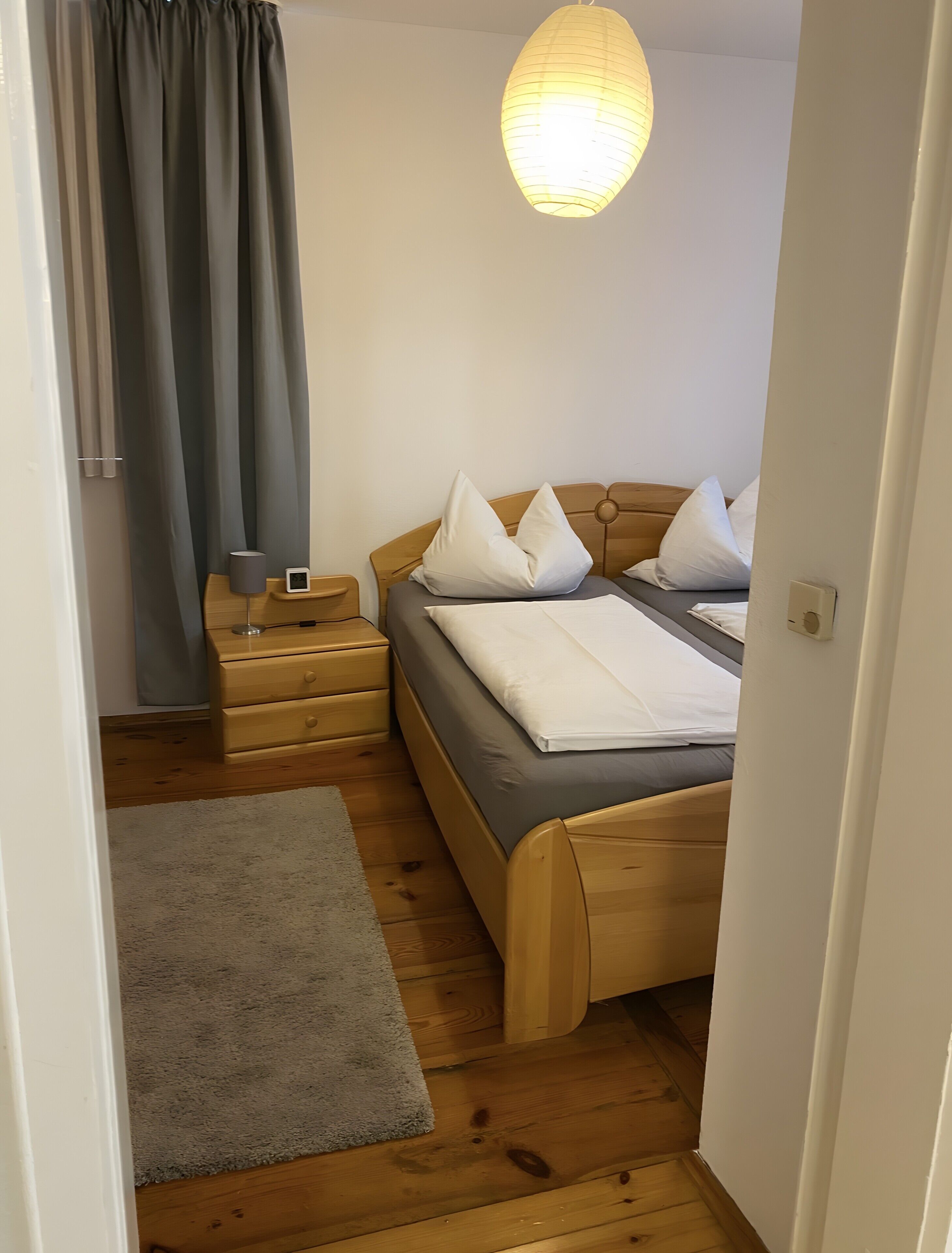 Ein Schlafzimmer mit einem Bett, Nachttischen, einer Lampe, einem Teppich und einer Pendelleuchte.