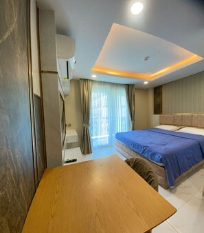 Relax in a stylish room with a made bed, wooden table, and large window.