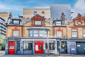 A hotel with a red facade, multiple windows, and a sign for a nearby restaurant.