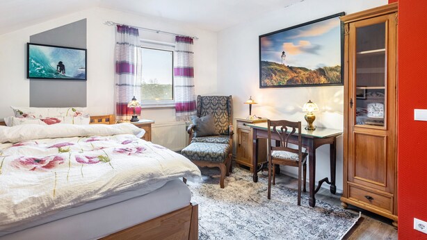 A bedroom with a bed, a desk, a chair, a cabinet, and two paintings on the walls. - Farmhouse 'Zur Henne' with Shared Terrace and Wi-Fi (Weinbach)