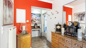 A hallway with a red wall, a wooden cabinet, a glass-top dresser, a mirror, and a door leading to another room. - Farmhouse 'Zur Henne' with Shared Terrace and Wi-Fi (Weinbach)