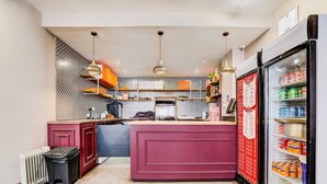 A compact kitchen with a central island, a refrigerator stocked with beverages, and a patterned backsplash.