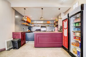 Una cocina compacta con una isla central, un refrigerador lleno de bebidas y un salpicadero decorativo.