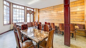 Una sala de conferencias con una gran mesa de madera y sillas, ventanas amplias y paneles de madera en la pared.