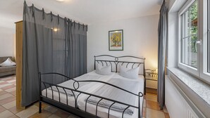 A bedroom with a bed, a window, a radiator, and a painting on the wall. - Apartment 'Haus 4' with Lake View, Shared Terrace and Wi-Fi (Meersburg)