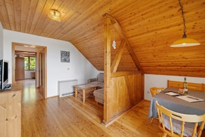 Ein Holzinterieur mit einem Esstisch, Stühlen, einer Couch und einem Fernseher.