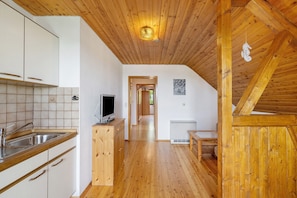 Eine Küche mit Holzausstattung, einem Fernseher und einer gefliesten Spritzschutzwand.
