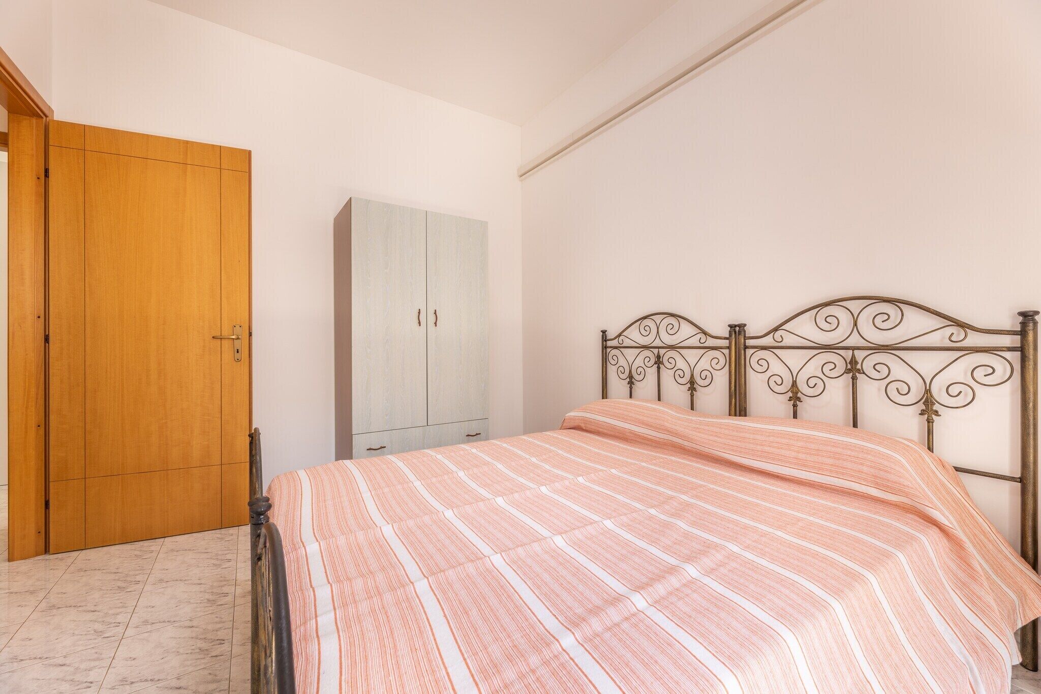 A bedroom with a bed, a wardrobe, and a cabinet.