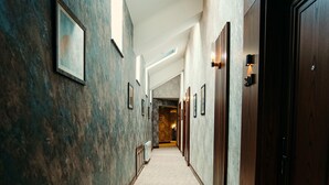 Un pasillo de hotel con alfombra estampada, cuadros enmarcados en las paredes y puertas de madera.