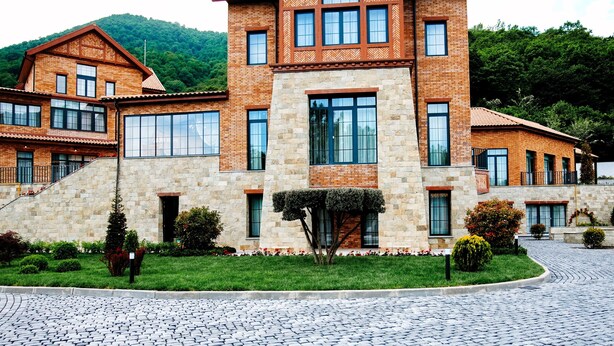 Un edificio grande de varios pisos con fachada de piedra y numerosas ventanas.