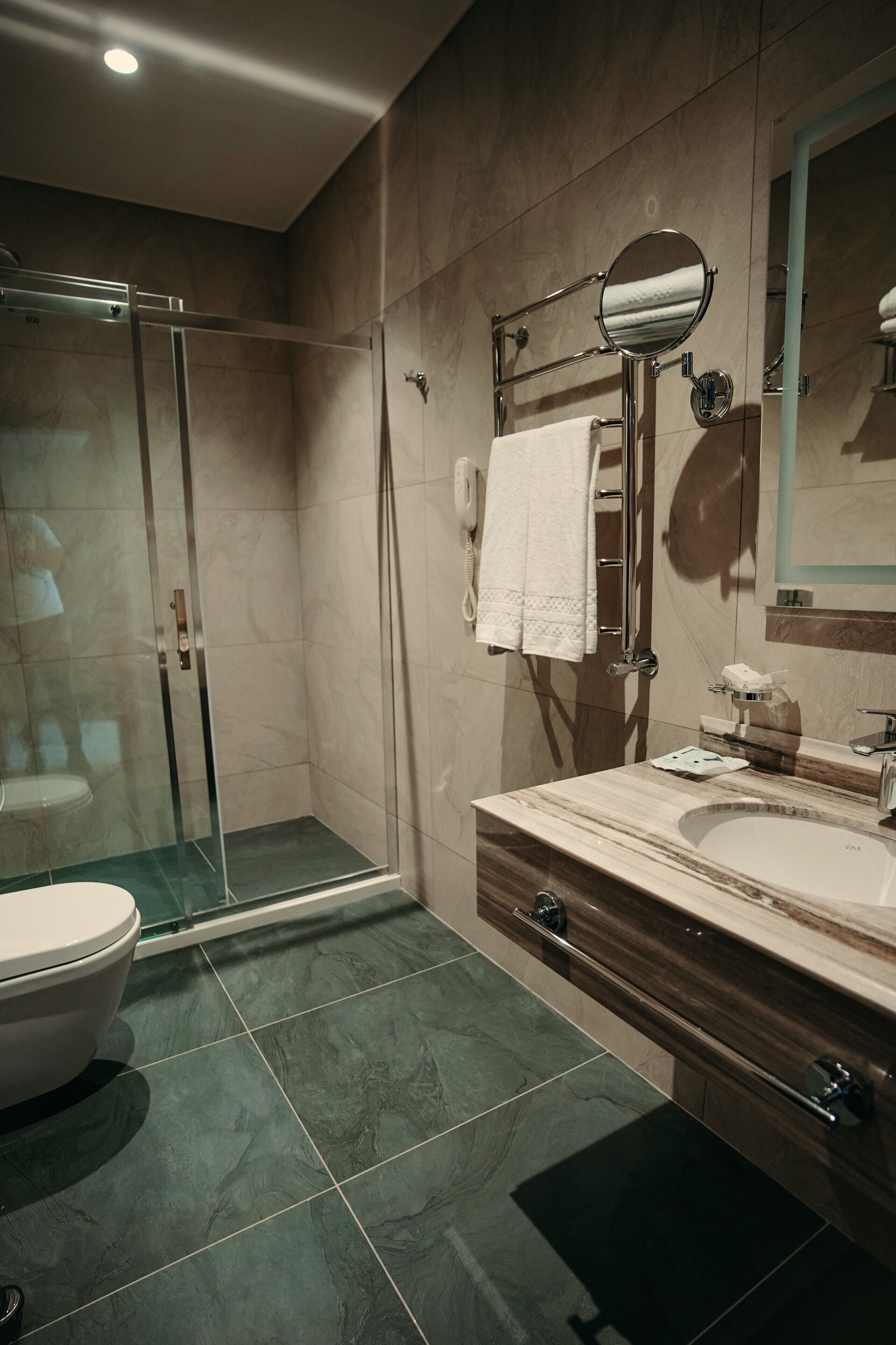 A modern bathroom with a glass-enclosed shower, a white toilet, a vanity with a sink, and a mirror.