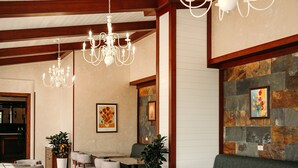 Un interior de restaurante con vigas de madera, candelabros, asientos acolchados y una pared de acento de piedra.