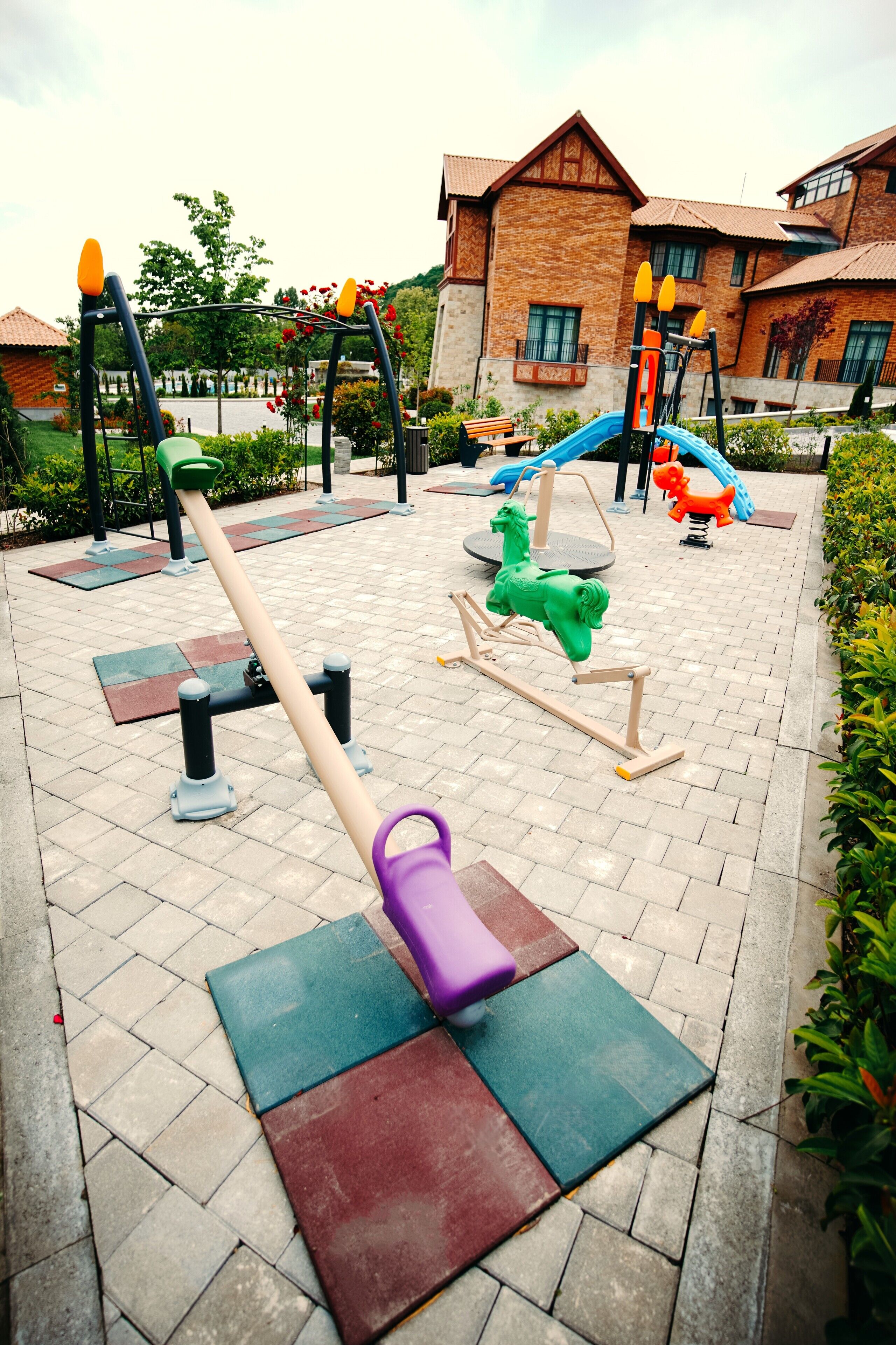 Un parque infantil con varios juegos, incluyendo columpios, un balancín y un carrusel.