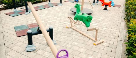 Un parque infantil con varios juegos, incluyendo columpios, un balancín y un carrusel.