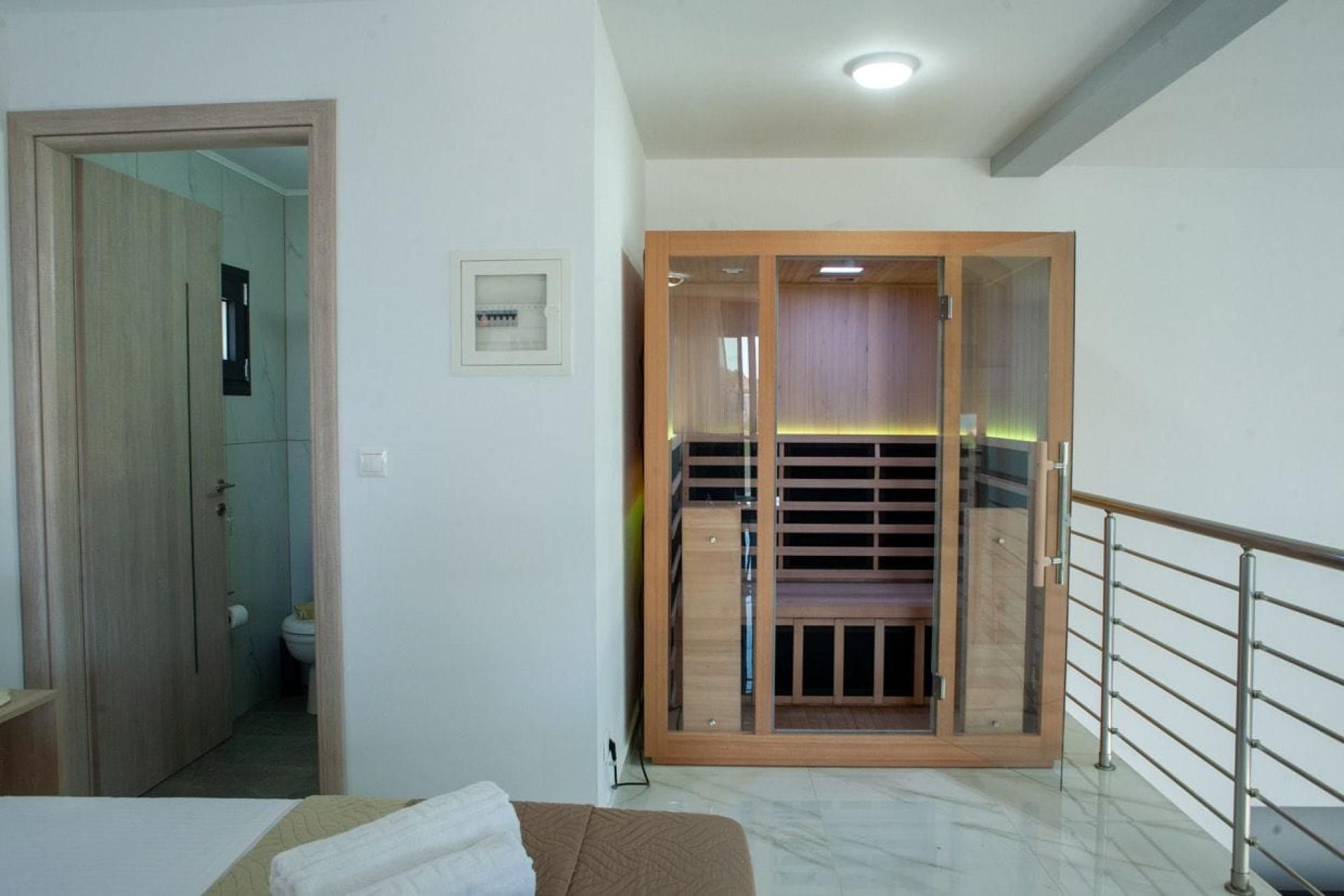 Habitación de hotel con armario de madera, cama, baño con inodoro y balcón con barandilla de metal.