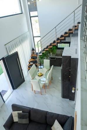A modern interior with a dining area, kitchen, staircase, and living room.
