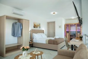 Una camera d'albergo moderna con un letto, un angolo salotto, un guardaroba e una televisione.