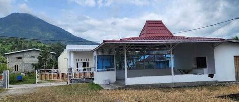 A two-story building with a red roof, a covered porch, and a view of a mountain.