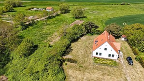 Eine Vogelperspektive eines ländlichen Anwesens mit einem großen weißen Haus, umgeben von grünen Feldern und Bäumen.