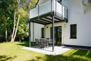 A modern house with a covered patio area, a dining table, and chairs. - Beachfront vacation rental with a terrace, access to the pool and sauna - Rex Rugia - Rex (Göhren)