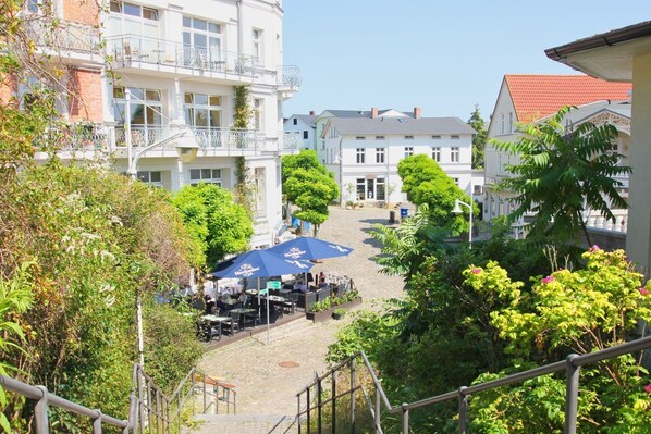 A courtyard with outdoor seating, surrounded by buildings with balconies and a red-tiled roof.