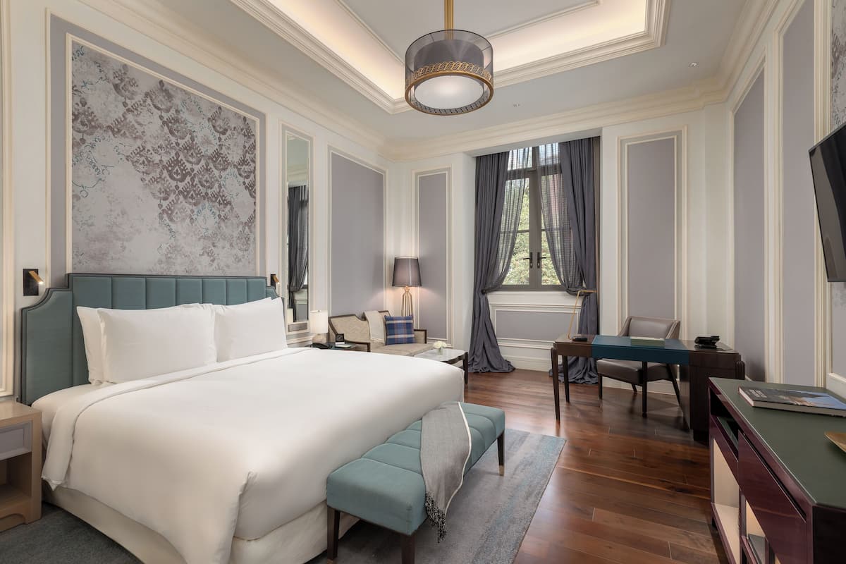 A spacious bedroom with a large bed, a desk, and a chair.