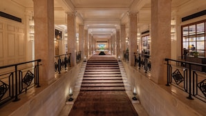 A grand hallway with marble columns, a carpeted staircase, and a view into a room with a large window. - The ERAVATI Sule Grand Yangon (Yangon)