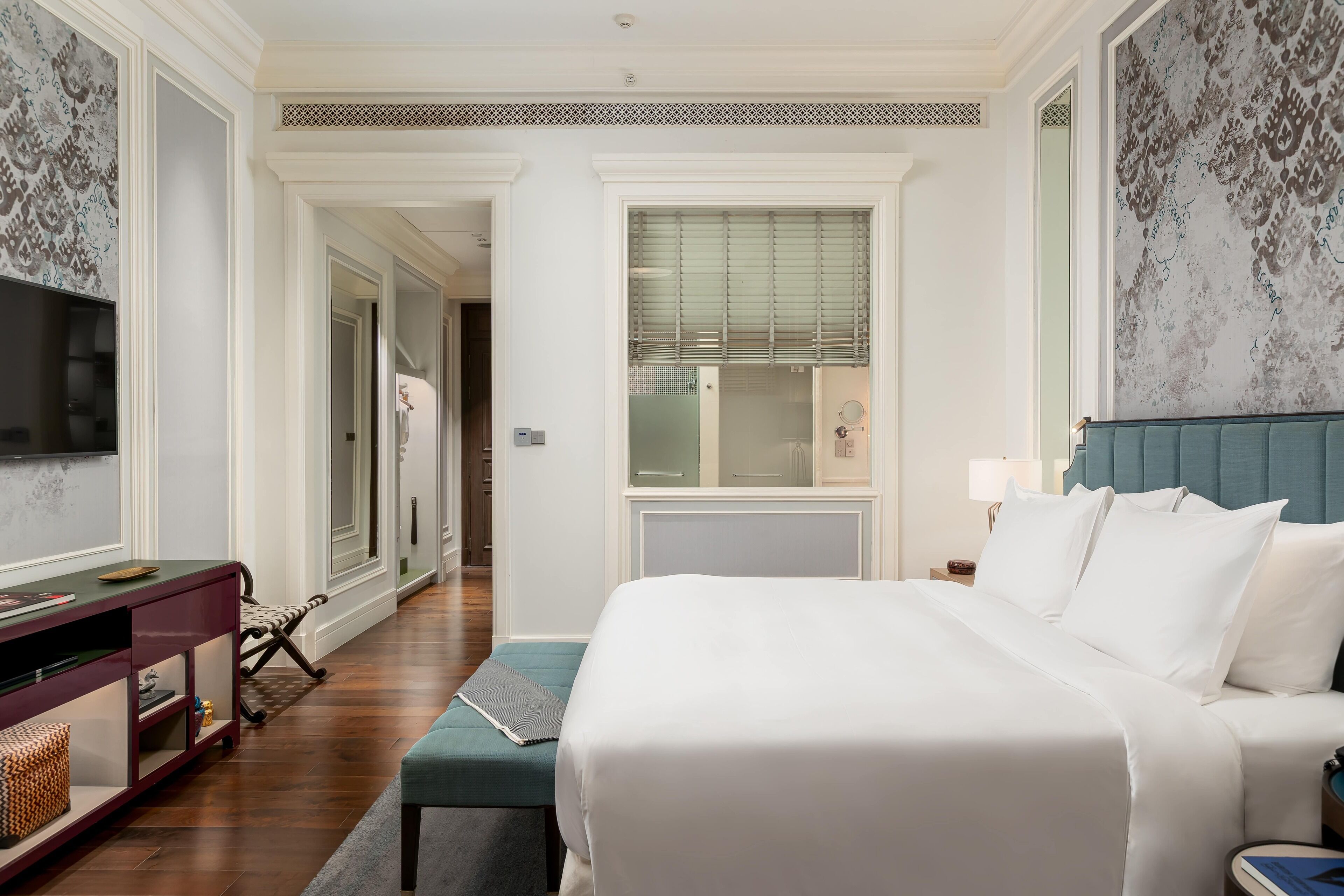 Een hotelkamer met een groot bed, een televisie, een bureau en een badkamer, zichtbaar door een geopende deur.