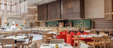 A spacious restaurant with high ceilings, modern lighting, and a variety of seating arrangements including tables and booths.