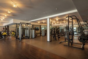 A gym with various exercise equipment, wooden flooring, and a mirrored wall.