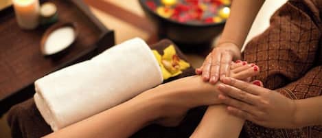 A foot massage session with a towel and candles on a tray.