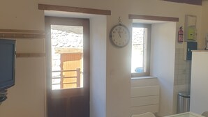 Une cuisine avec une table à manger, des chaises, une horloge et une fenêtre.