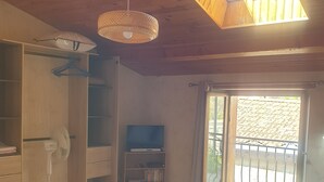 Une chambre avec un puits de lumière, un lit, une armoire et un meuble pour la télévision.