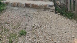 Un escalier en pierre mène à un bâtiment doté d’un mur en pierre et d’une clôture en bois.