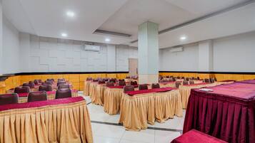 Un salón de conferencias con varias mesas y sillas dispuestas en filas.
