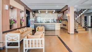 A hotel lobby with a reception desk, sofas, a staircase, and a modern interior design. - Townhouse Oak Padang near RTH Imam Bonjol (Padang)
