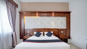 A hotel room with a large bed, wooden headboard, two bedside tables, and a nightstand with a lamp. - Townhouse Oak Padang near RTH Imam Bonjol (Padang)