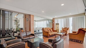 A spacious lobby with leather sofas, a glass coffee table, and a large mirror. - Townhouse Oak Padang near RTH Imam Bonjol (Padang)