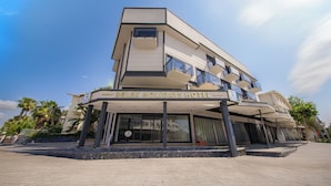 Ett hotell med modern design, med en framträdande balkong och en tydlig skylt med texten ”BELEK HOLIDAYS HOTEL”.