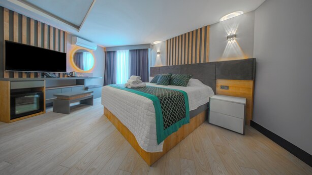 Ett modernt hotellrum med en stor säng, en TV, ett skrivbord och en minibar.