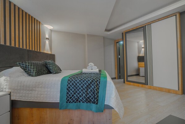 A modern bedroom with a bed, bedside table, and a large mirror. - Belek hollidays hotel (Serik)