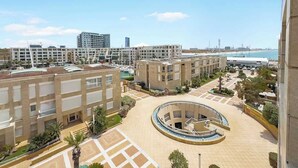 A modern building complex with multiple floors, a central courtyard, and a view of the sea.
