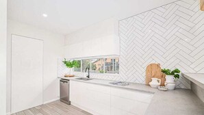 Una cuina moderna amb armaris blancs, una falca decorativa a la paret i un rentaplats, a més d'una finestra amb vistes.