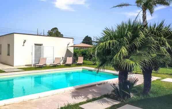 Una piscina amb gandules i un edifici petit amb una porta i finestres.